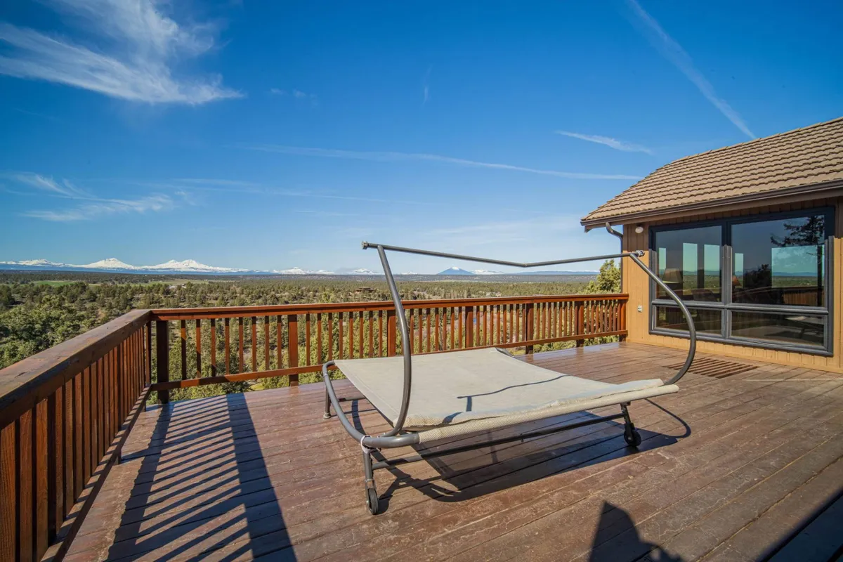 A lounge chair is positioned on a deck with a panoramic view beyond the railing—mountains and open skies dominate the horizon, while the peaceful mood invites sunbathing, reading, or simply soaking up the natural beauty.