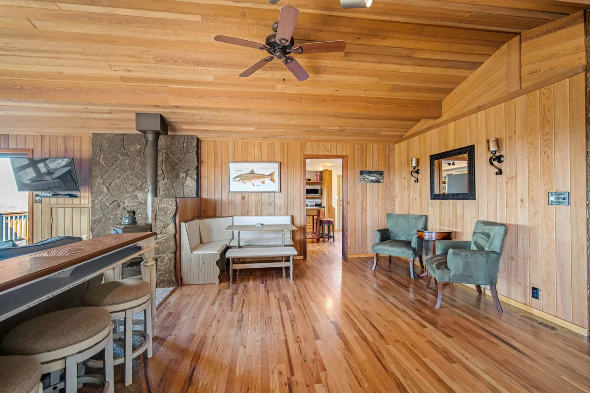 A welcoming interior space featuring a wooden ceiling, stone fireplace, bar counter, and seating area. The ambiance is relaxed and social, making it a natural hub for post-adventure relaxation or group play.