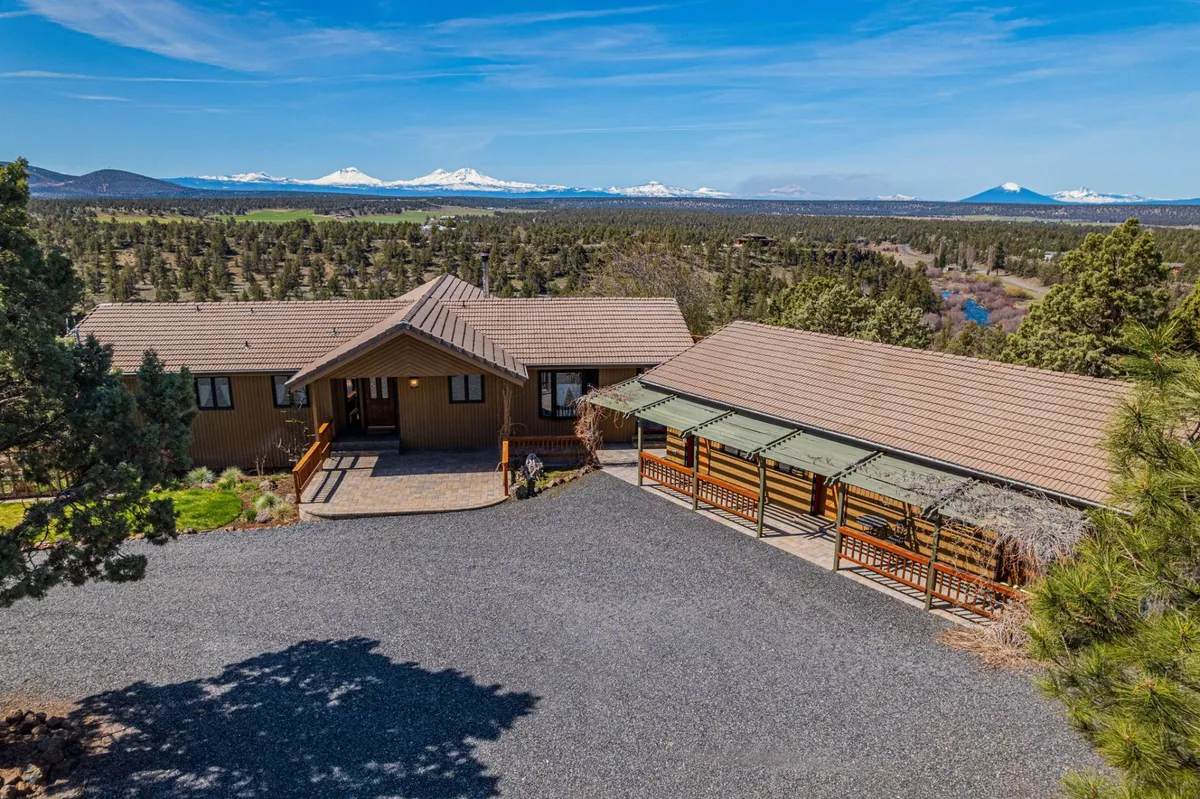 The main house and garage seen from outside, framed by natural landscaping and a dramatic mountain range in the background. The tranquil mood and expansive setting highlight the property’s connection to wide-open spaces and the rugged terrain Central Oregon is known for.